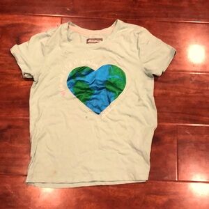 A girls shirt that is green and blue saying the world is full of adventures